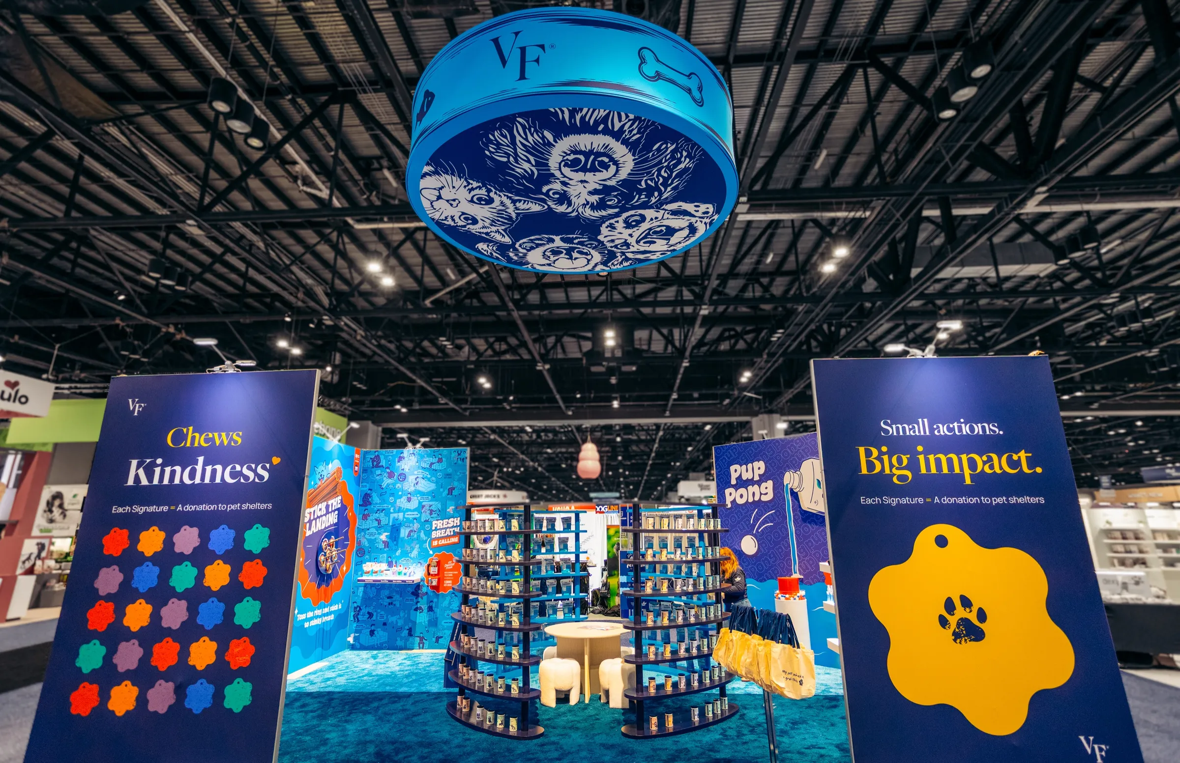 Synergy Labs booth at Global Pet Expo with a suspended drum sign and branded towers