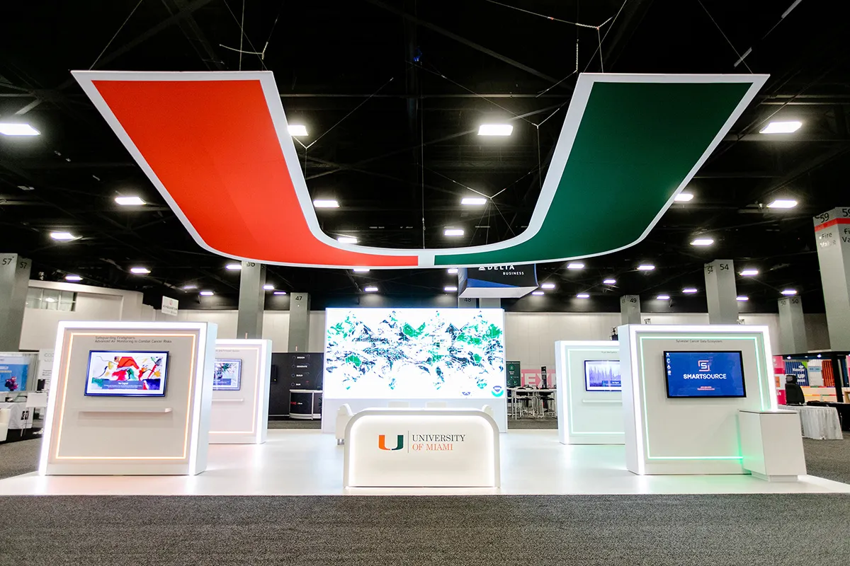University of Miami exhibit at eMerge Americas with the U logo overhead and white kiosks