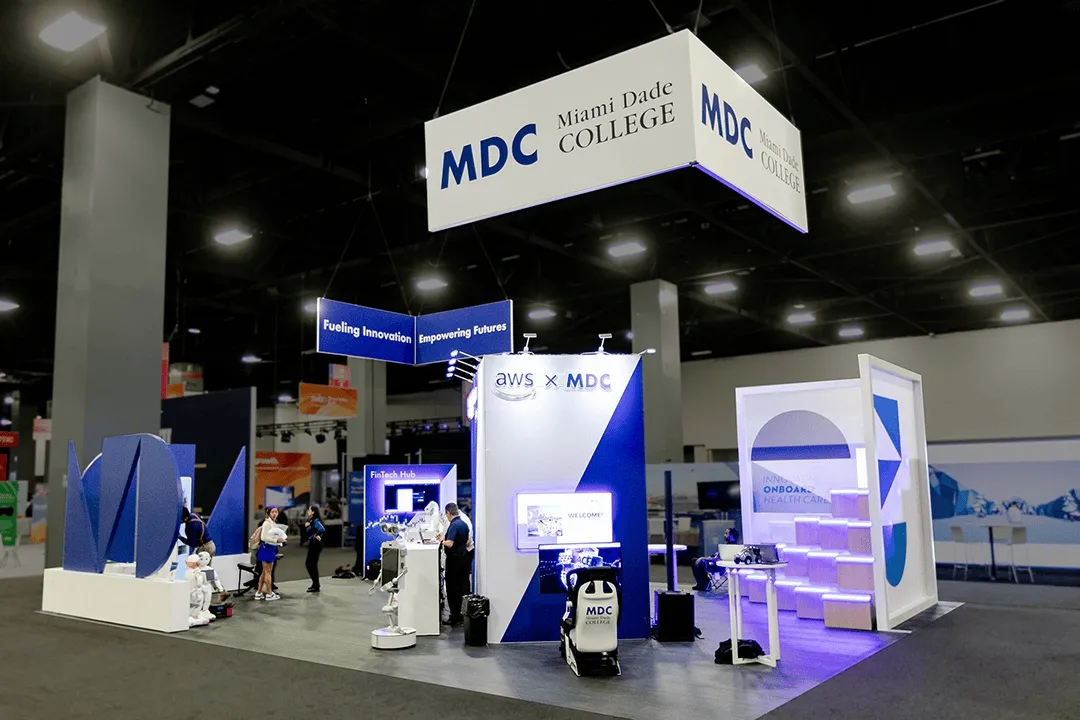 Large custom trade show booth in Orlando featuring interactive tech hubs, LED-lit display structures and a large hanging banner
