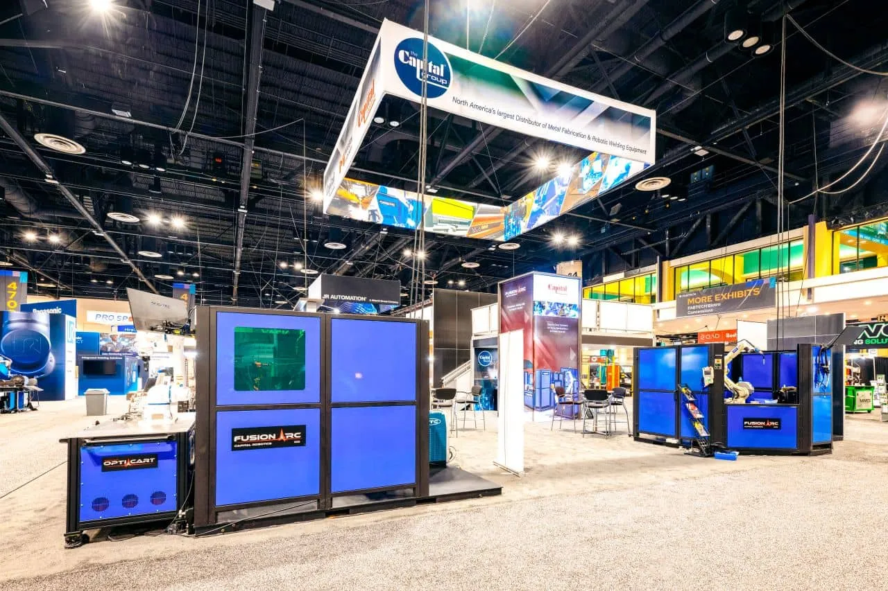 Large industrial trade show booth for The Capital Group, featuring heavy machinery and a large hanging sign