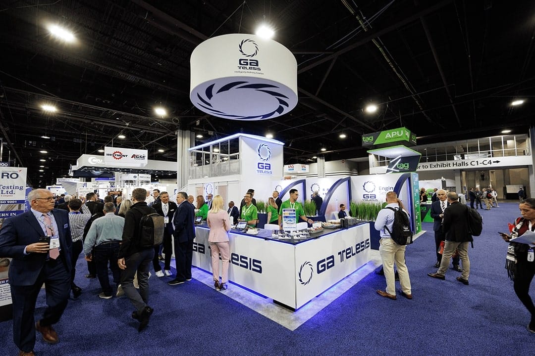 Busy exhibition hall with GA Telesis booth and attendees.